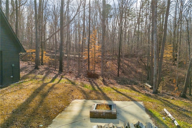 view of yard with an outdoor fire pit and a wooded view