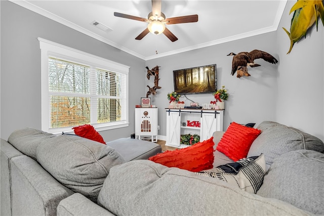 living area with baseboards, a ceiling fan, visible vents, and crown molding