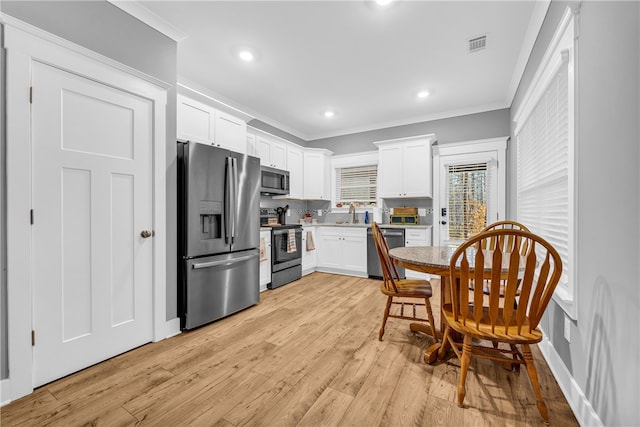 kitchen with visible vents, white cabinetry, ornamental molding, appliances with stainless steel finishes, and light wood-type flooring