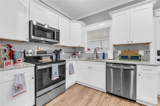 kitchen with appliances with stainless steel finishes, crown molding, a sink, and backsplash