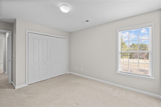 unfurnished bedroom featuring carpet, a closet, visible vents, and baseboards