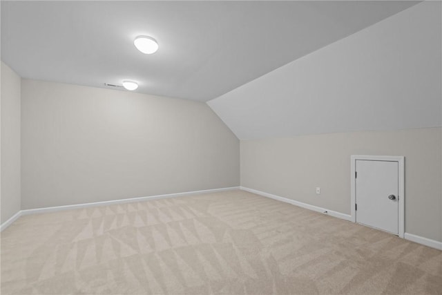 additional living space with vaulted ceiling, baseboards, and light colored carpet