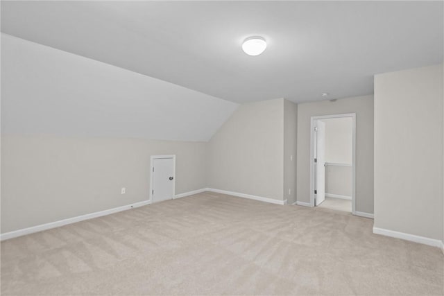 bonus room featuring lofted ceiling, light carpet, and baseboards