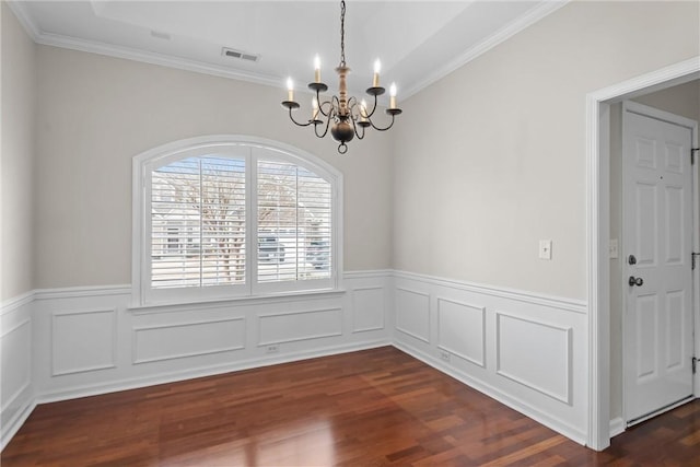 unfurnished dining area with visible vents, wainscoting, dark wood-style floors, crown molding, and a chandelier