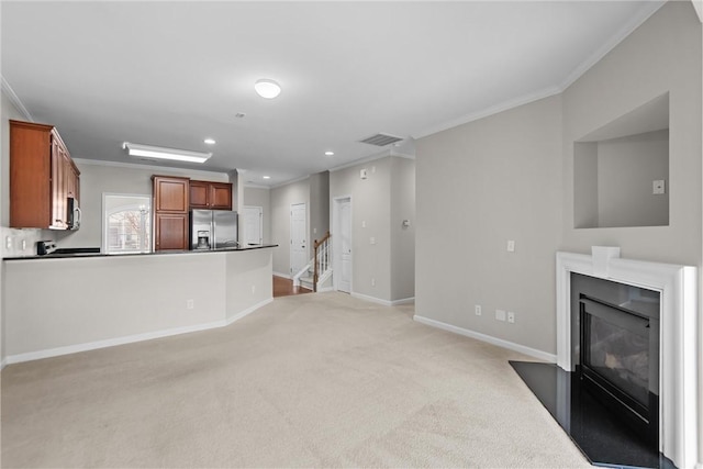 unfurnished living room featuring light carpet, a fireplace with flush hearth, visible vents, and crown molding