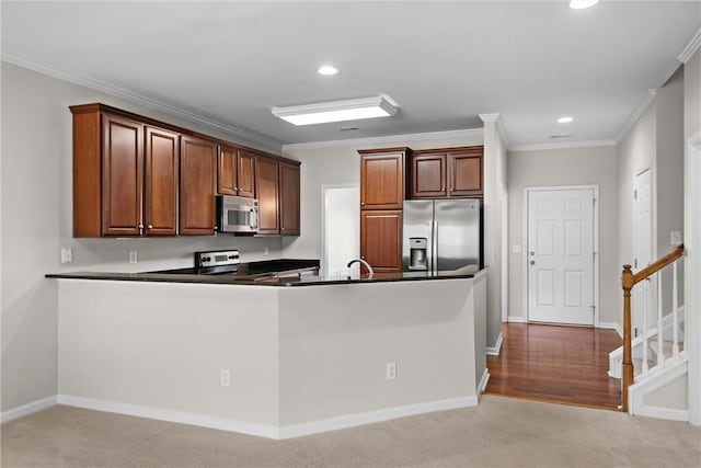 kitchen featuring dark countertops, appliances with stainless steel finishes, carpet flooring, and ornamental molding