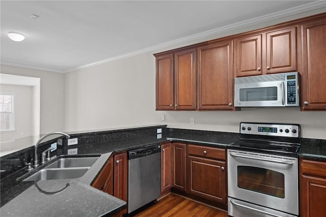 kitchen with ornamental molding, dark stone countertops, dark wood-style flooring, stainless steel appliances, and a sink