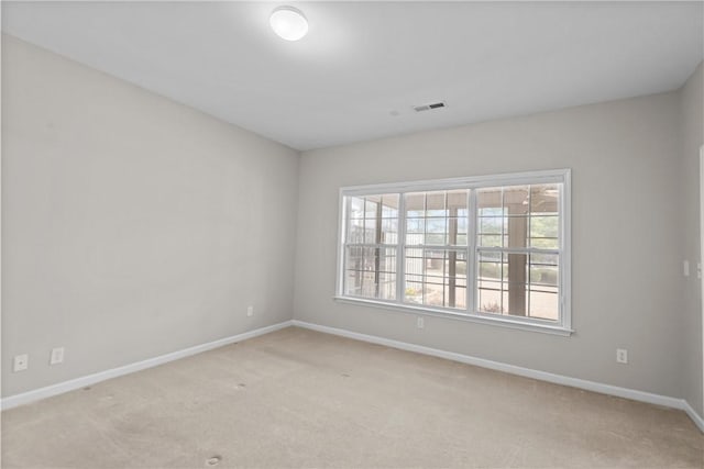 empty room with light carpet, visible vents, and baseboards