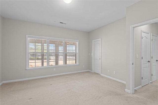 unfurnished room featuring light carpet, baseboards, visible vents, and a healthy amount of sunlight