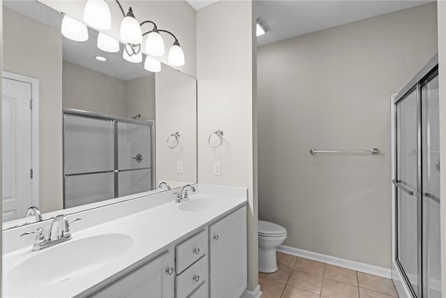 bathroom featuring a stall shower, a sink, toilet, and tile patterned floors