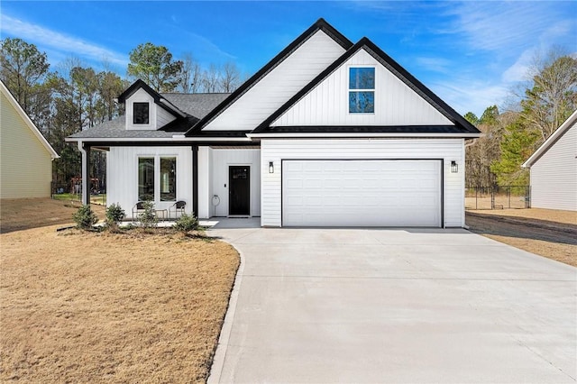 modern inspired farmhouse featuring a garage, covered porch, and driveway