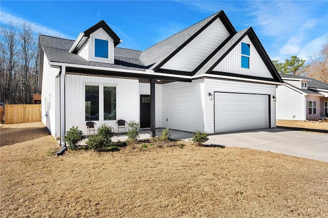 modern inspired farmhouse featuring concrete driveway, an attached garage, and fence