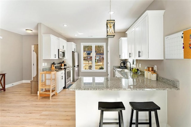 kitchen with light wood-type flooring, a breakfast bar, white cabinets, and stainless steel appliances