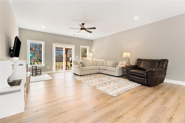 living room with light wood-style floors, baseboards, and a ceiling fan