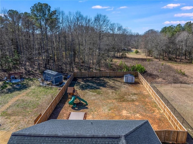 view of yard with a storage unit, fence, a playground, and an outdoor structure