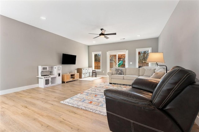 living room featuring a ceiling fan, recessed lighting, baseboards, and light wood finished floors