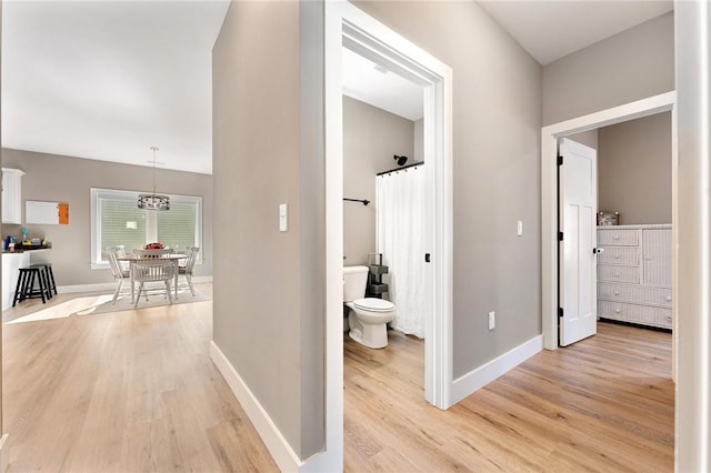 corridor featuring baseboards and light wood finished floors