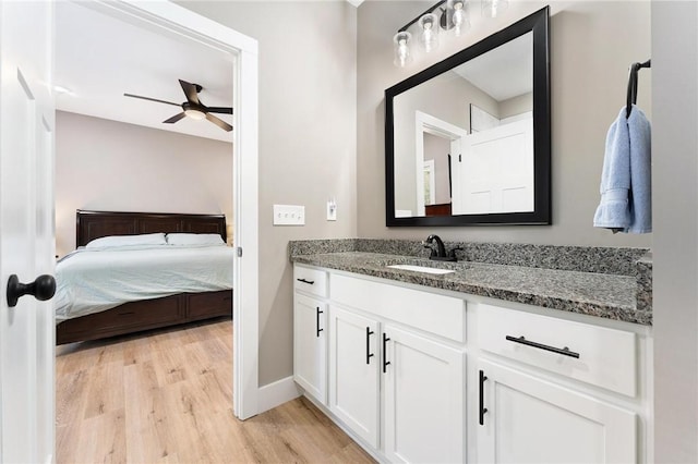 bathroom featuring ceiling fan, wood finished floors, vanity, baseboards, and ensuite bath