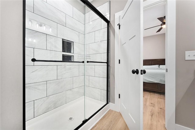 full bath featuring a stall shower, connected bathroom, a ceiling fan, and wood finished floors