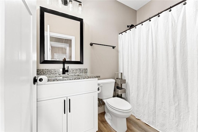 bathroom featuring toilet, a shower with curtain, wood finished floors, and vanity