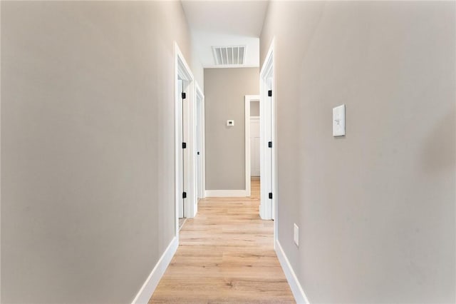 hall featuring light wood-style floors, visible vents, and baseboards