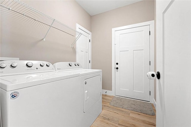 laundry area with laundry area, baseboards, washer and clothes dryer, and light wood-style floors