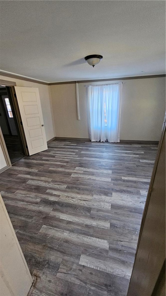 unfurnished bedroom with dark wood-style floors, crown molding, a textured ceiling, and baseboards