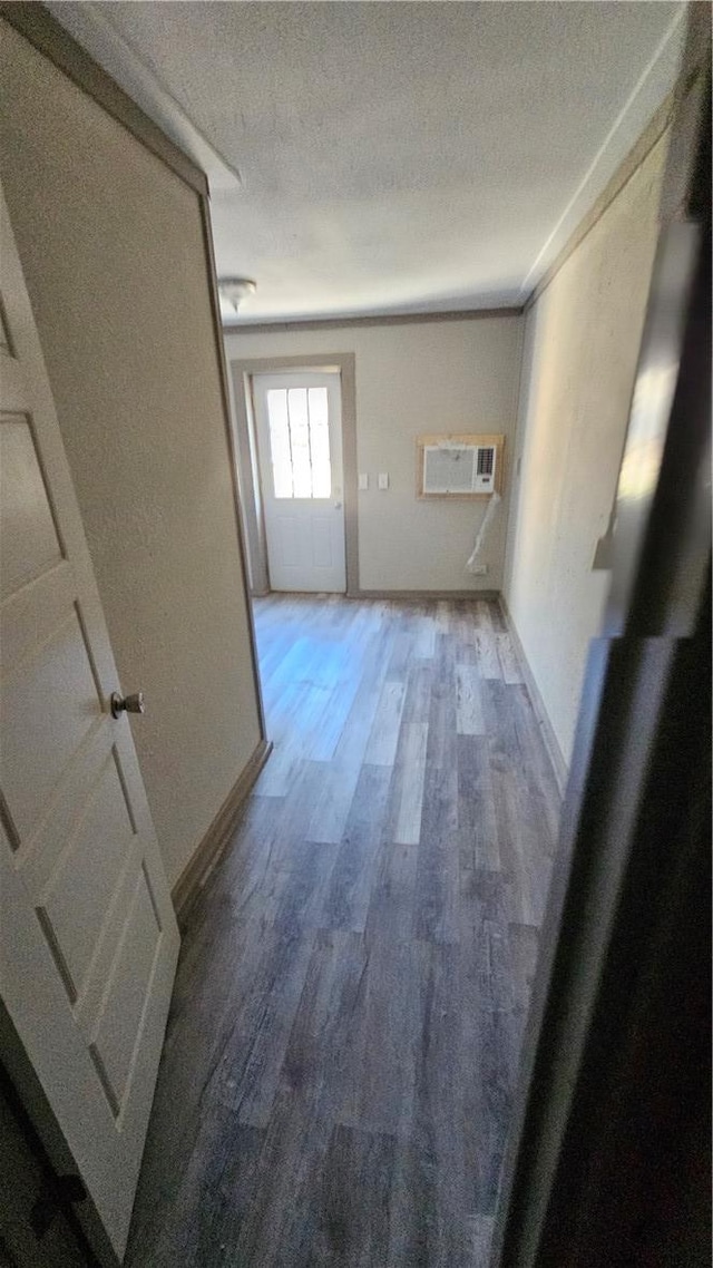 corridor featuring a textured ceiling, baseboards, and wood finished floors