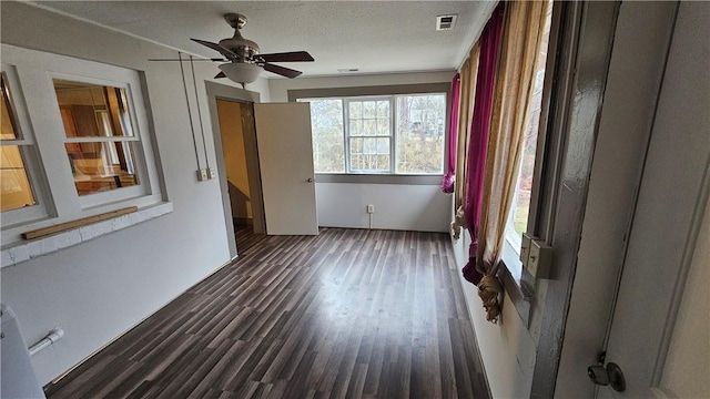 unfurnished room with ceiling fan, a textured ceiling, visible vents, and wood finished floors