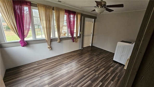 unfurnished room featuring dark wood-type flooring, a ceiling fan, a wealth of natural light, and radiator