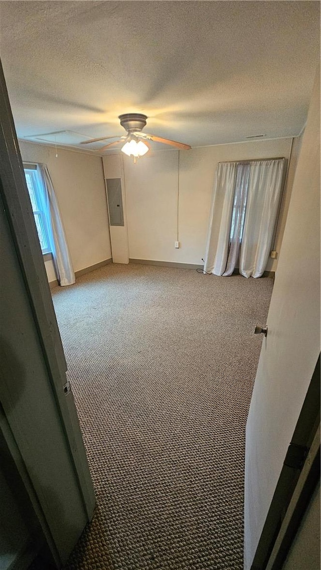 interior space with light carpet, attic access, electric panel, a ceiling fan, and a textured ceiling