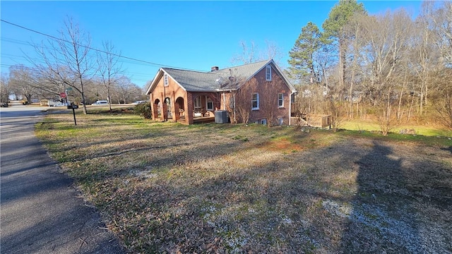 view of property exterior with brick siding and a chimney