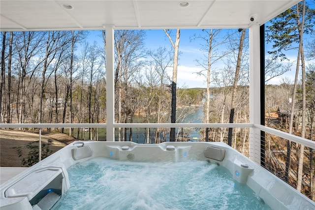 unfurnished sunroom with a hot tub and a view of trees