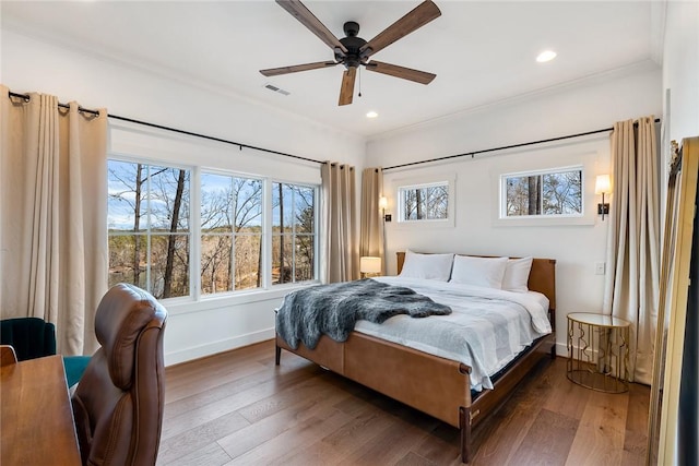 bedroom featuring crown molding, visible vents, baseboards, and wood finished floors