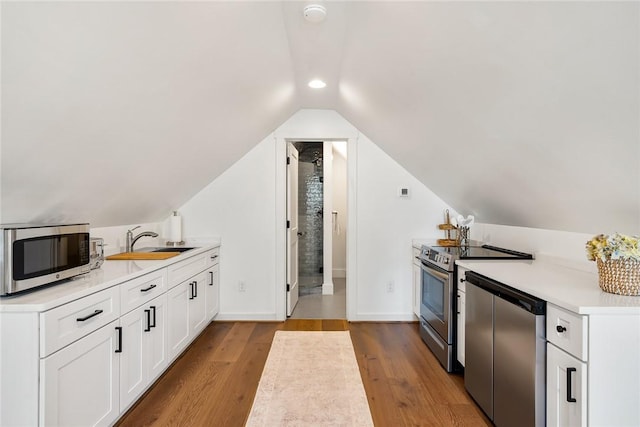 kitchen with stainless steel appliances, wood finished floors, a sink, white cabinets, and light countertops