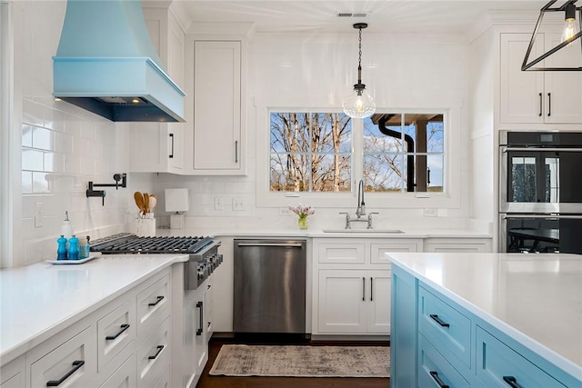 kitchen with decorative backsplash, appliances with stainless steel finishes, white cabinetry, a sink, and premium range hood