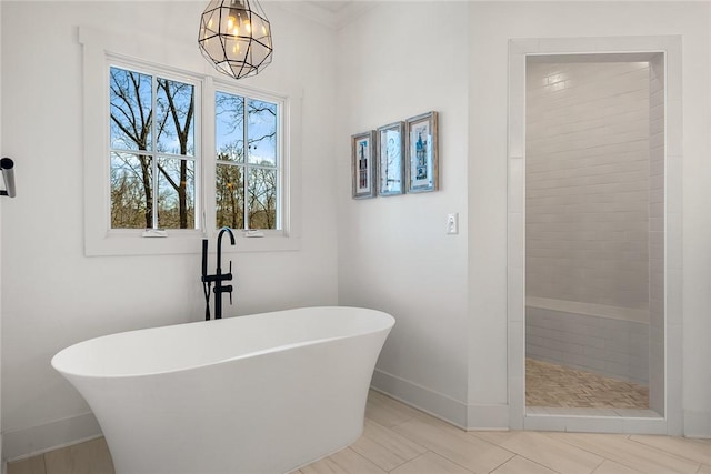 full bath with a chandelier, tiled shower, a soaking tub, and baseboards