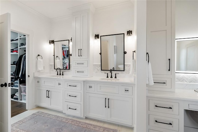 full bath with double vanity, ornamental molding, a walk in closet, and a sink