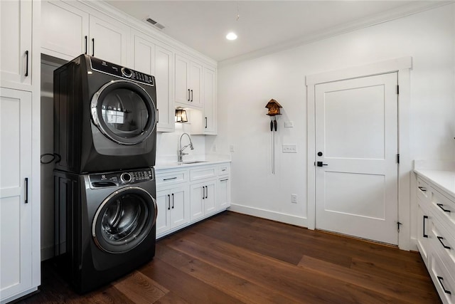 laundry area with recessed lighting, dark wood-style flooring, a sink, stacked washing maching and dryer, and cabinet space