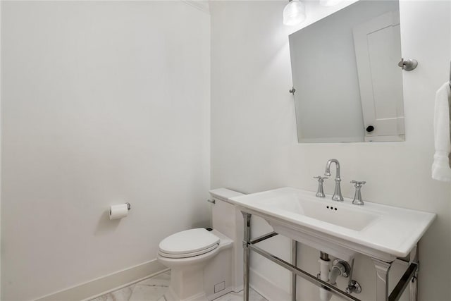 half bathroom featuring toilet, marble finish floor, baseboards, and a sink