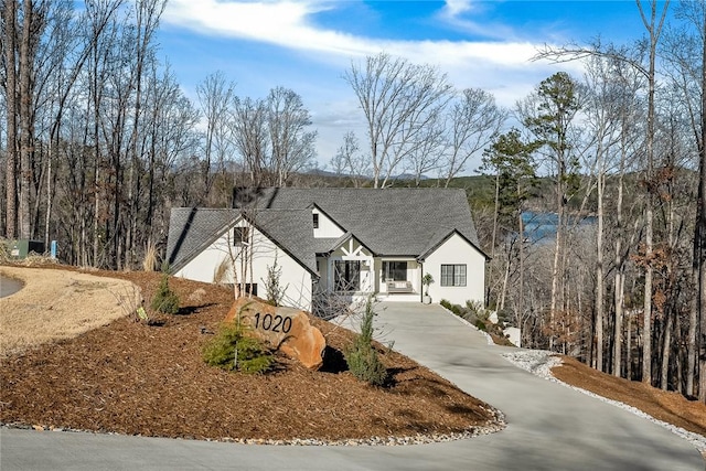 view of front of property featuring driveway, roof with shingles, and stucco siding