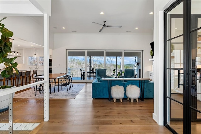 living area with ceiling fan, ornamental molding, wood finished floors, and recessed lighting