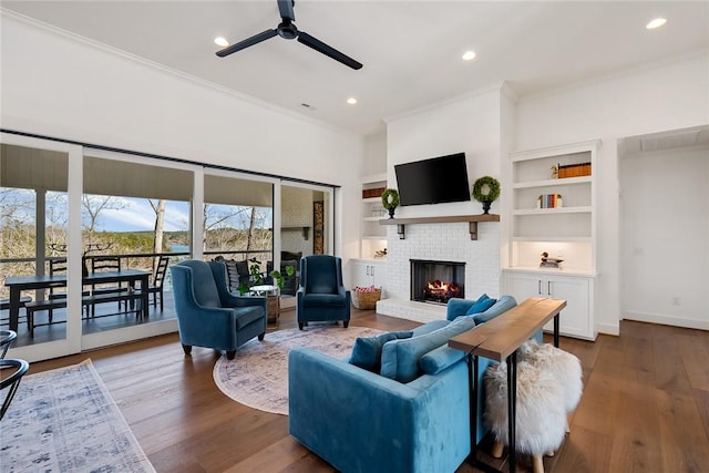 living room with a fireplace, baseboards, crown molding, and wood finished floors