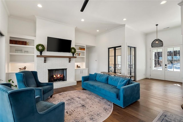 living room with dark wood-style floors, french doors, a fireplace, crown molding, and recessed lighting