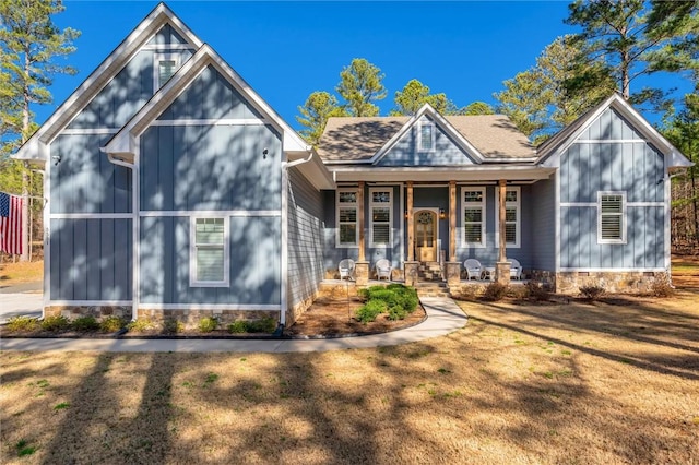 view of front of home with a porch, a front yard, and roof with shingles