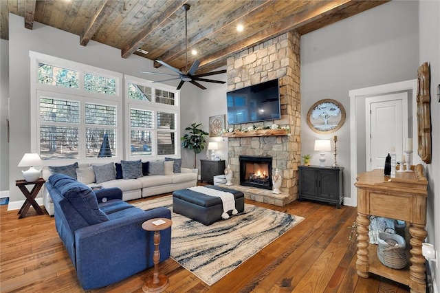 living area featuring high vaulted ceiling, wooden ceiling, wood-type flooring, and a stone fireplace