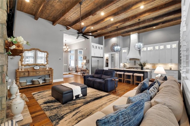 living area featuring beam ceiling, a high ceiling, wood ceiling, wood finished floors, and baseboards