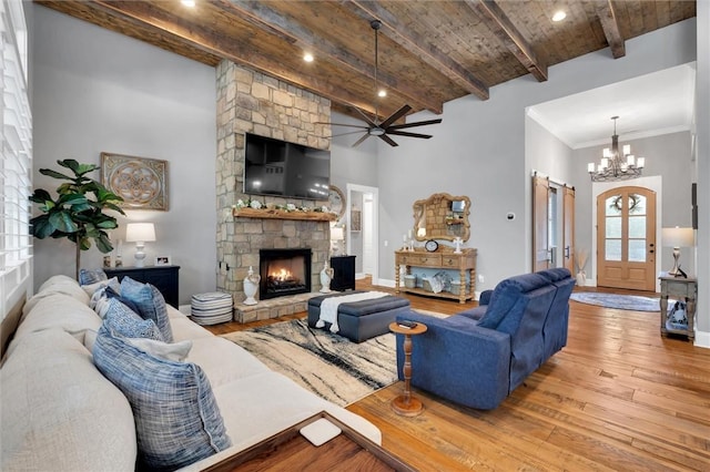 living room with wood-type flooring, a stone fireplace, high vaulted ceiling, beamed ceiling, and baseboards