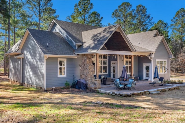 back of property featuring a patio area, a lawn, and roof with shingles