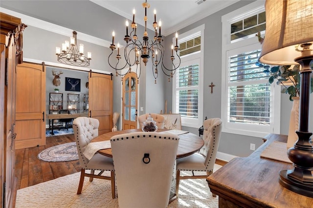 dining room featuring a healthy amount of sunlight, a barn door, ornamental molding, and wood-type flooring